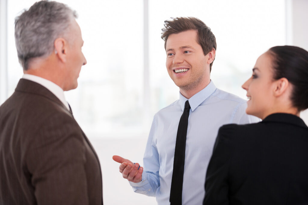 Two sales and marketing interns talking to an older client